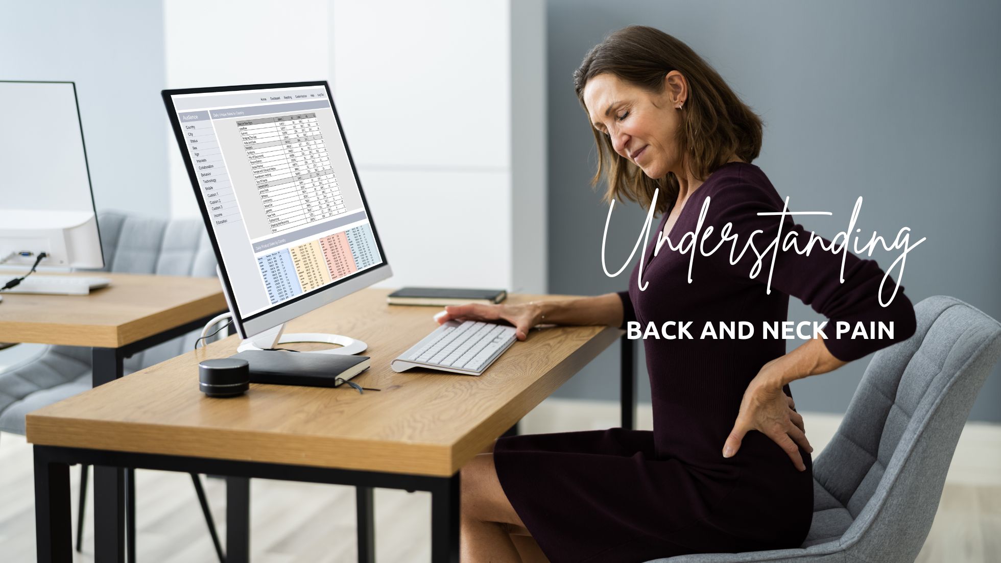 Woman sits at a desk holding her sore back